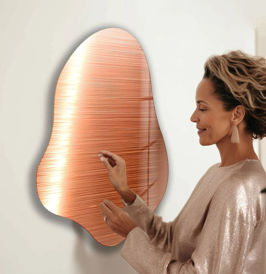 Abstract rose gold glass wall art with flowing lines and a shimmering texture.