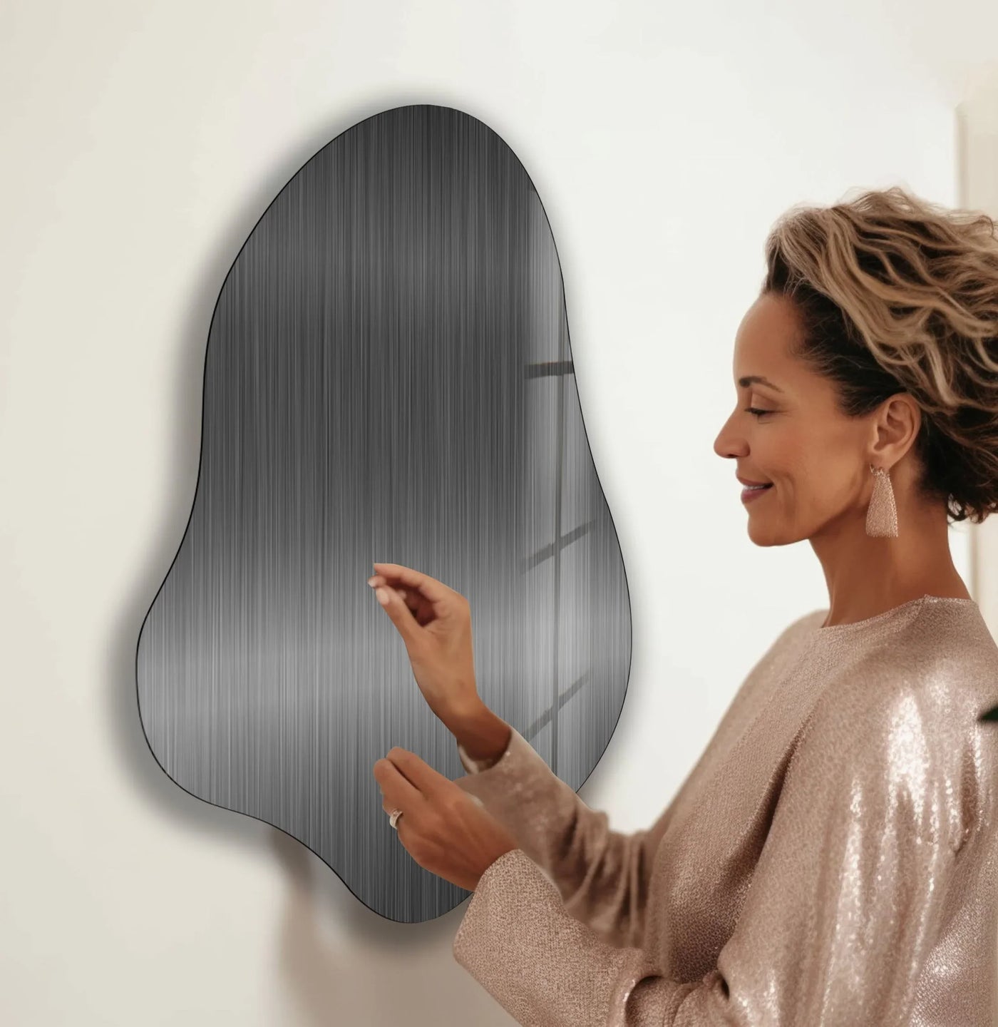 A woman touches a brushed metal abstract wall art, showcasing its sleek finish as part of home decor.