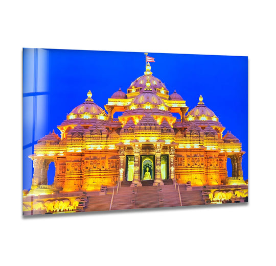 Dramatic color contrast showcases the Akshardham Temple in this glass wall art, where warm, golden lights accentuate its architectural details against a deep blue sky, perfect for home decoration.