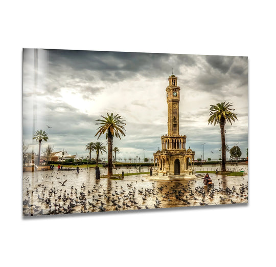 Illuminating the Izmir Clock Tower glass art, the brightest area highlights the sunset's soft glow on this iconic landmark, with pigeons scattered around the landmark.