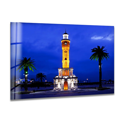 Horizontal and rectangular Izmir Clock Tower glass wall art wall prints showcase the iconic Turkish landmark illuminated at night, flanked by palm trees.