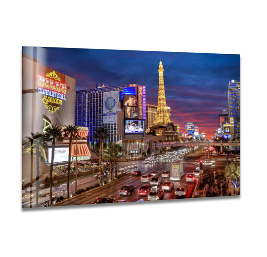 Deep blues and radiant oranges dominate this Las Vegas Nightlife glass printing wall art, showcasing a vibrant cityscape with iconic casinos and the Eiffel Tower replica.