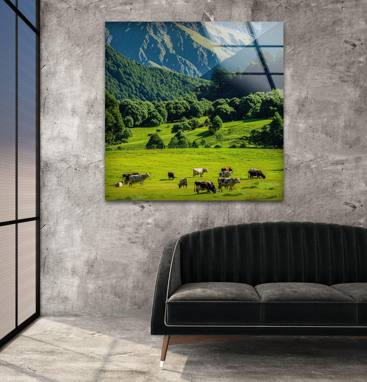 A peaceful mountain valley with rolling green hills, grazing cows, and a dramatic alpine backdrop.
