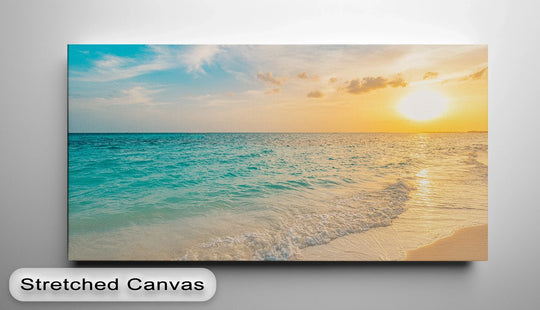 The focal point of the serene ocean sunset landscape shows canvas pictures with turquoise waves meeting the sandy shore under a radiant, golden sky.