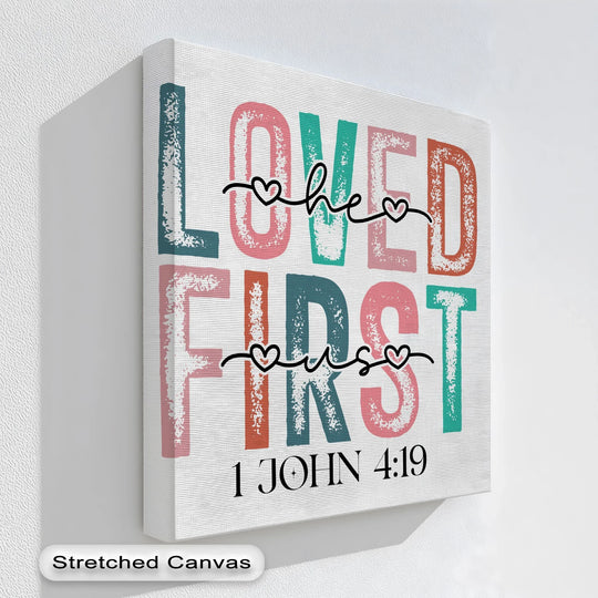 Brightly colored 'Loved He First' lettering visually dominates this Christian framed canvas print inspired by 1 John 4:19.