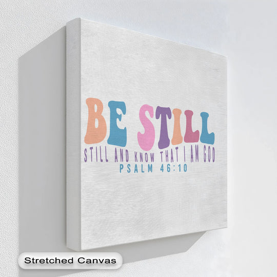 White is the dominant color of this scripture-inspired hanging canvas print featuring the words 'Be Still – Psalm 46:10'.