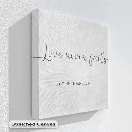 'Love never fails' in elegant script defines the central subject of this textured canvas painting showcasing 1 Corinthians 13:8.
