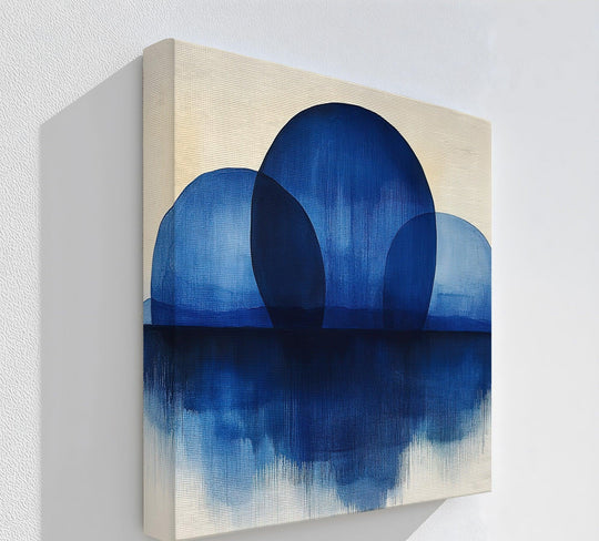 Notice the textured canvas surface of this unique canvas print showcasing minimalist blue abstract spheres seemingly reflected in still indigo-colored water.
