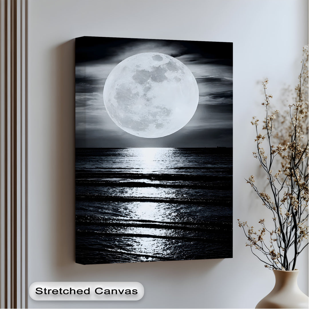 The abstract quality of this big canvas print highlights the dramatic contrast of a radiant full moon casting a shimmering path across the dark, rippling ocean.