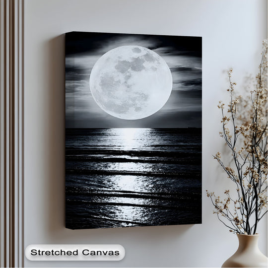 The abstract quality of this big canvas print highlights the dramatic contrast of a radiant full moon casting a shimmering path across the dark, rippling ocean.