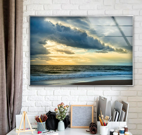 Abundant negative space above the desk emphasizes the dramatic stormlight horizon in this ocean glass wall art, showcasing impressive glass printing detail.