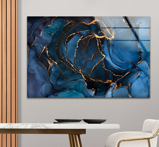 A moody sapphire and gold fluid ink glass print offers unique modern wall decor, evoking a sense of luxurious depth.