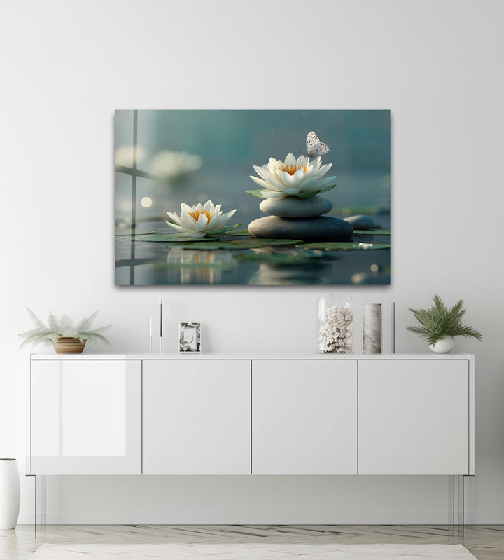 The balanced stack of smooth, grey stones provides a central geometric element for a serene lotus and butterfly glass printing.