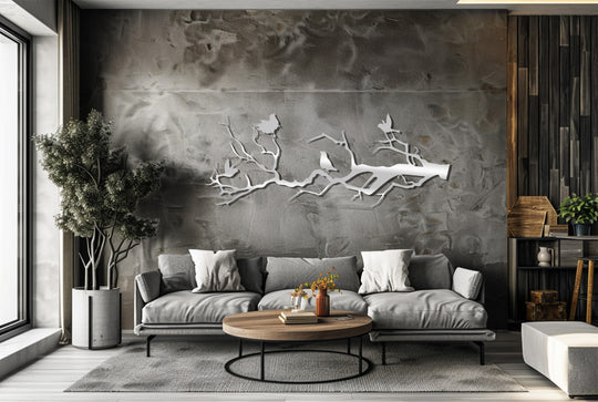 Low color saturation highlights the silver birds on branch metal wall decor, a nature-inspired silhouette adding elegance to this gray living space.