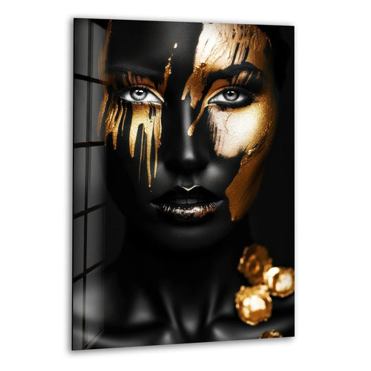 A striking portrait showcases a woman's face adorned with dripping gold paint over a matte black finish, printed on tempered glass wall art.