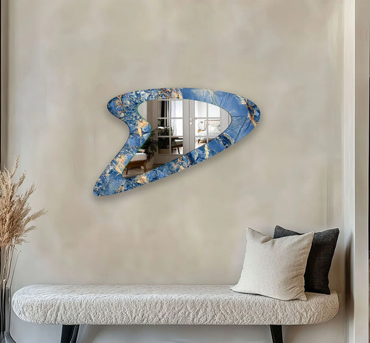 An abstract blue and gold asymmetric mirror with an irregular shape reflecting a stylish room an entryway mirror on a light wall