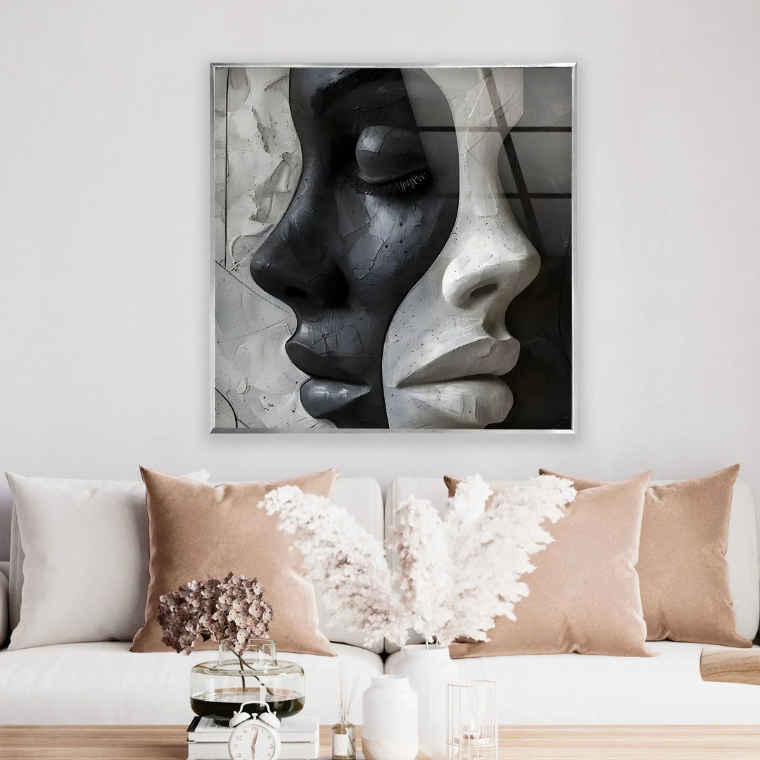 Abstract monochrome artwork on glass showing intertwined female profiles blending dark and light tones.