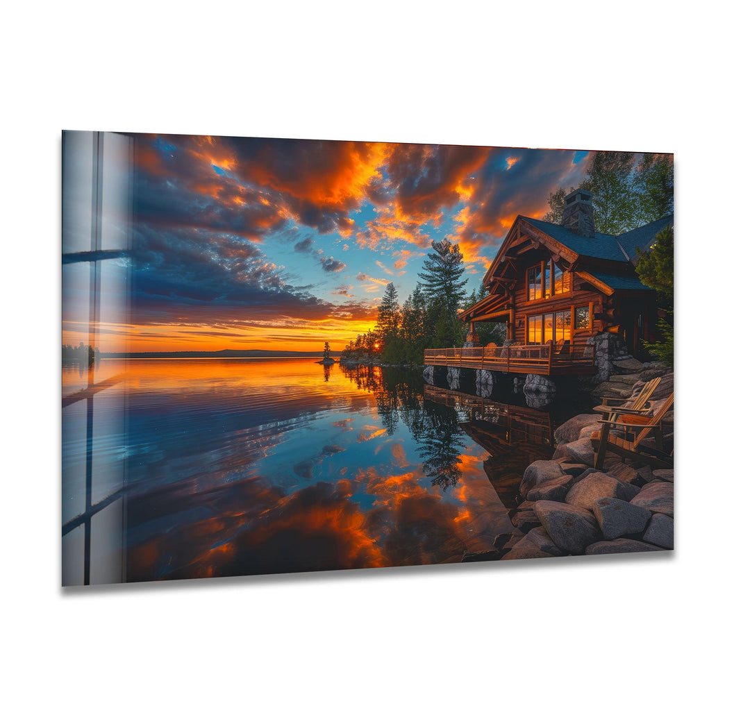 Glass wall art featuring a cozy lakeside cabin illuminated by a stunning sunset.

