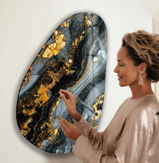 A woman admires an asymmetrical oval black and gold detailed glass wall art decor.