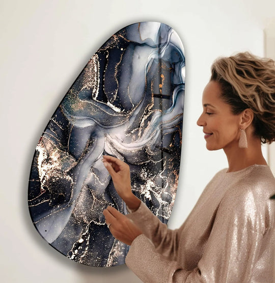 Asymmetrical oval black and grey marble glass hanging wall art with swirling gold accents.