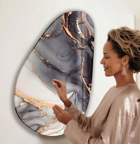 A woman admires the textured, marbled surface of this black, white, and golden glass wall art decor.
