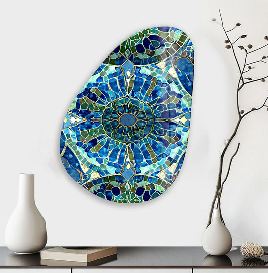 An asymmetrical oval blue mosaic design glass wall art features a textured, multi-faceted surface with shimmering glass pieces creating a stained-glass effect.