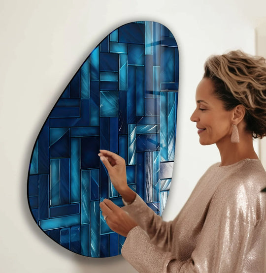 A woman admires the reflective gleam of decorative wall art on an asymmetrical oval navy blue glass piece, highlighting bright lines.