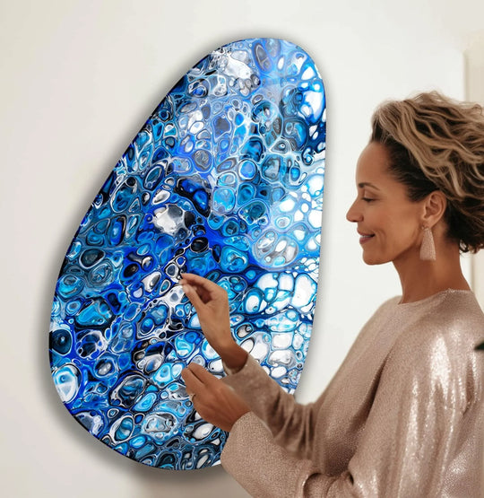 A woman admires a striking oval glass art piece with mesmerizing cell-like geometric patterns in deep blues and white.