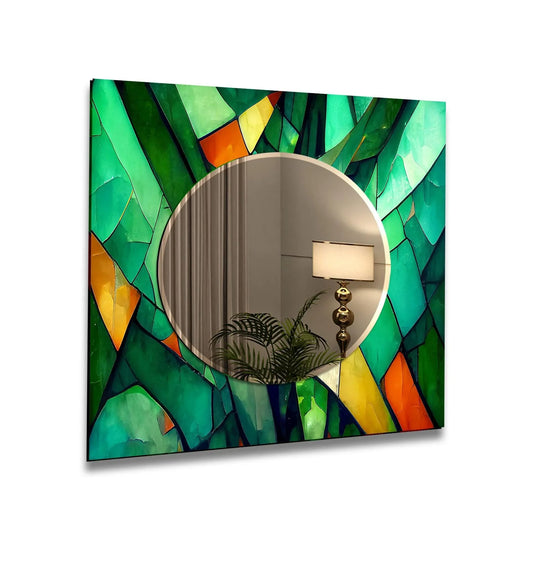 The stained glass wall mirror features green and orange geometric shapes and abstract art and it is a decorative wall mirror that reflects a lamp and plant