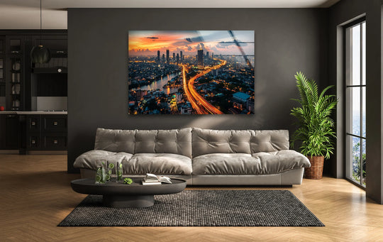 Bangkok Night glass wall art showcases a vibrant city skyline and flowing lights and offers modern wall decor for a living room above a gray sofa