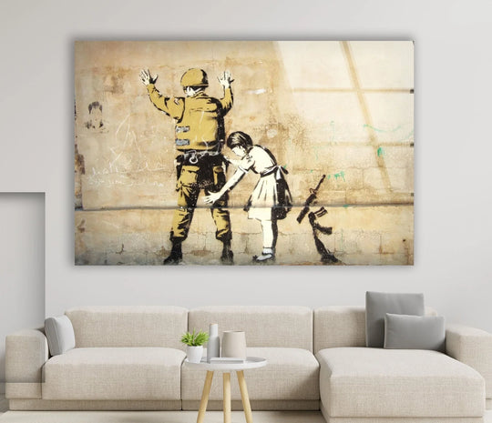 Banksy glass wall art featuring the iconic Girl Frisking Soldier street artwork with a child and soldier on a beige wall