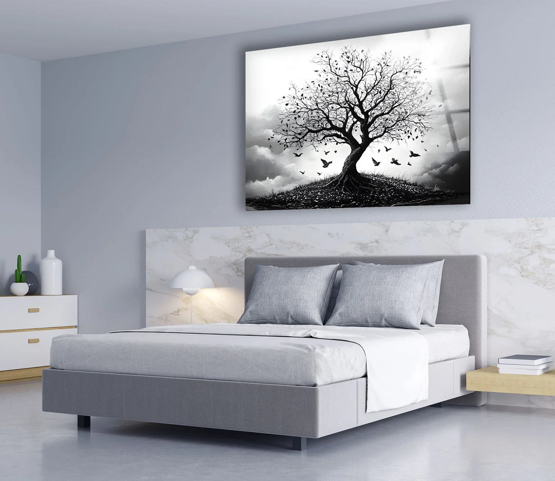 Black and white tree illustration on glass set against dramatic clouds with birds taking flight.