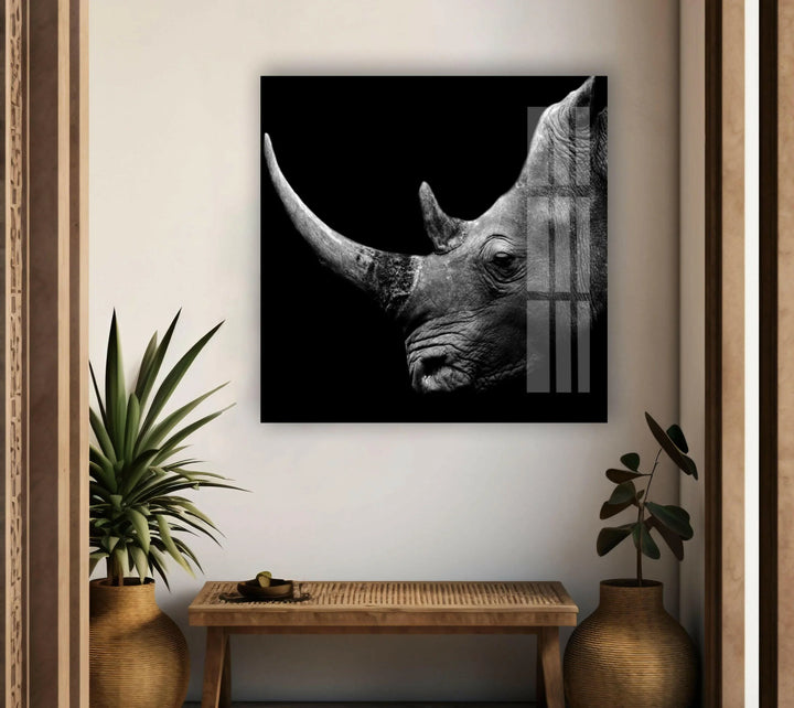 Grayscale wildlife portrait on glass highlighting the textured skin and long horn of a rhinoceros.