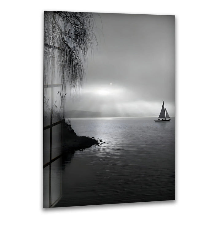 Black and white glass wall art of a sailboat drifting on calm water under soft sun rays.