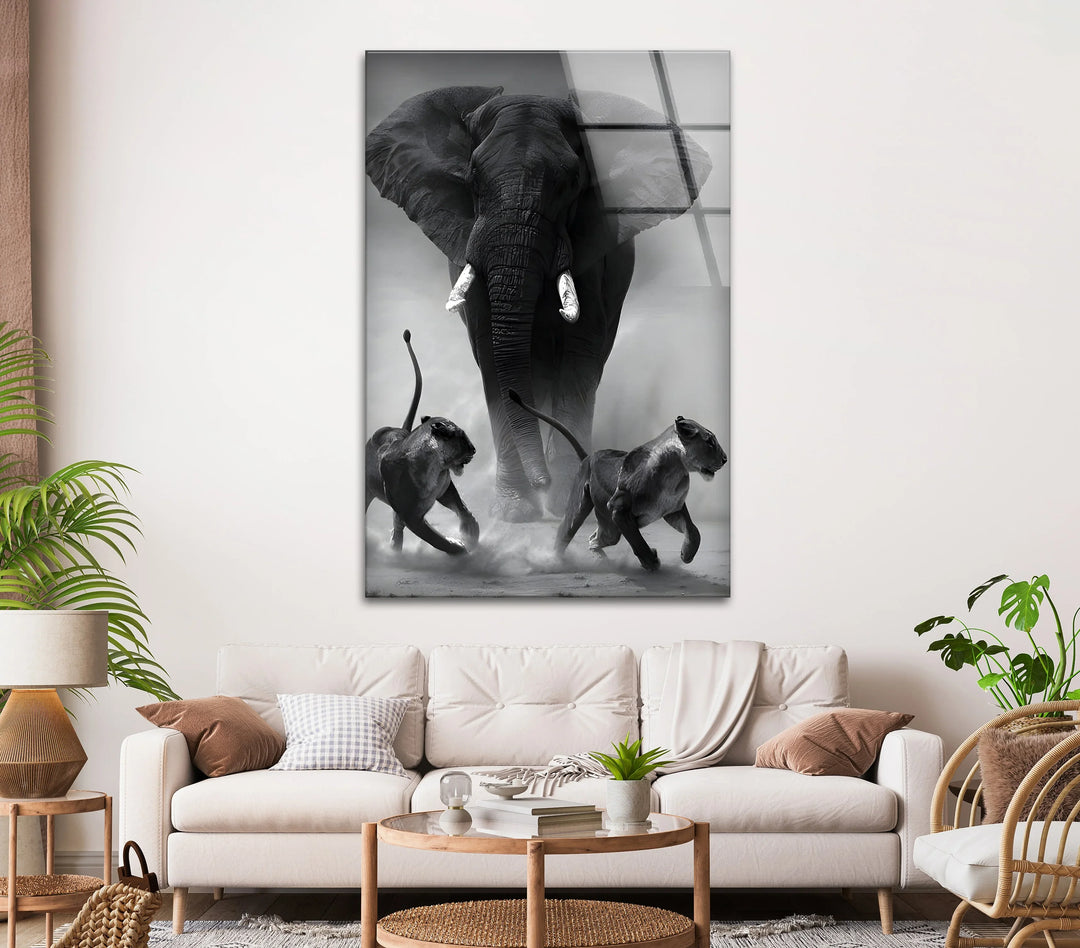 Glass wall art depicting an elephant advancing through dust behind two running lions.