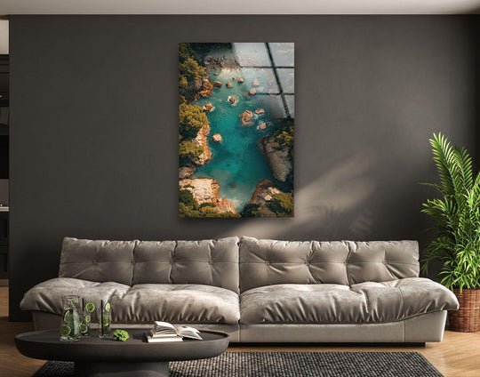 In the foreground, a round coffee table displays refreshments and books, complementing the turquoise cove aerial hanging wall art displayed above the couch.
