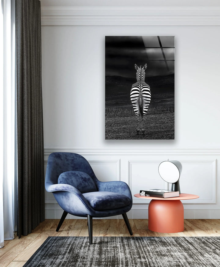 Black and white landscape featuring a single zebra from behind in a dark, textured environment.