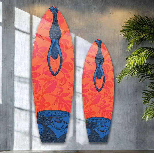 Two vibrant mermaid surfboard glass wall artwork pieces create a visual rhythm against a textured wall with dappled light.