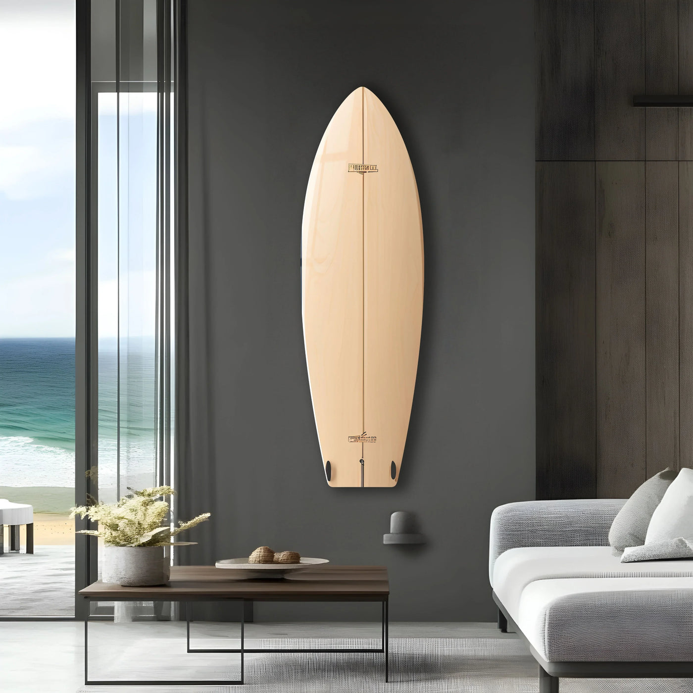 A minimalist beige surfboard, a focal point on layered dark walls, is a striking piece of decorative wall art overlooking a serene ocean scene.