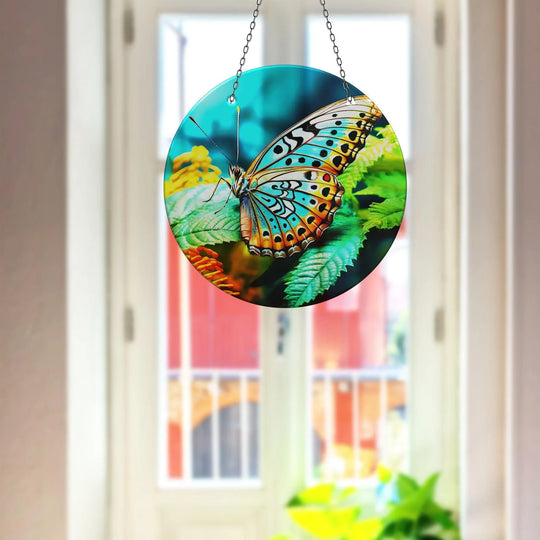 Evoking a sense of gentle flight, the detailed blue butterfly seems to flutter on this round glass wall artwork suncatcher, catching the light with poised movement.