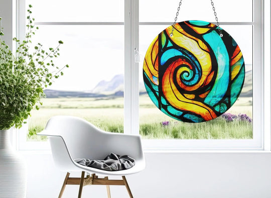 Horizontally oriented round glass suncatcher showcases an orange and blue fractal design that brings a touch of decorative wall art to brighten any window space.