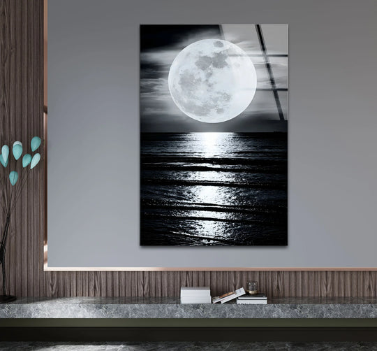 Striking color contrast showcases a black and white moon landscape glass wall art, creating a unique modern wall decor display with a luminous full moon over a dark sea.