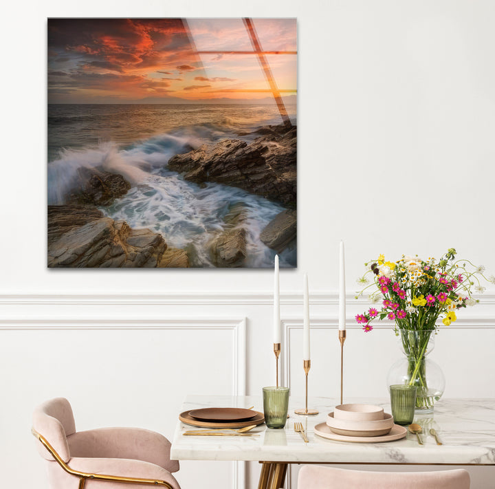 Wandkunst mit Sonnenuntergang an der Felsküste – Dramatisches Glasdruckdesign mit Meereswellen