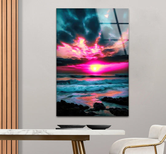 Glass wall art showing dark foreground rocks leading to bright pink sunset surf and aqua ocean swells.