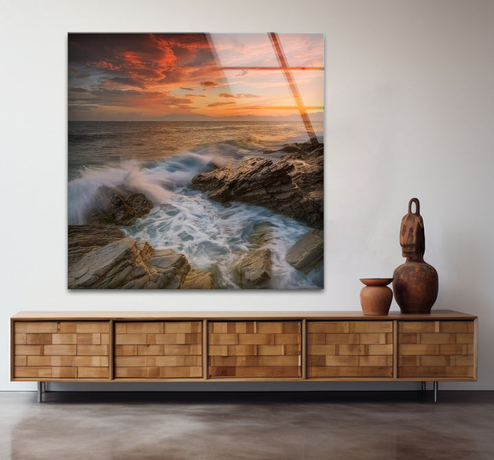 Wandkunst mit Sonnenuntergang an der Felsküste – Dramatisches Glasdruckdesign mit Meereswellen