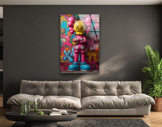 The Kaws glass wall art features pink and yellow hues and is unique decor and cool art and modern decor for modern spaces