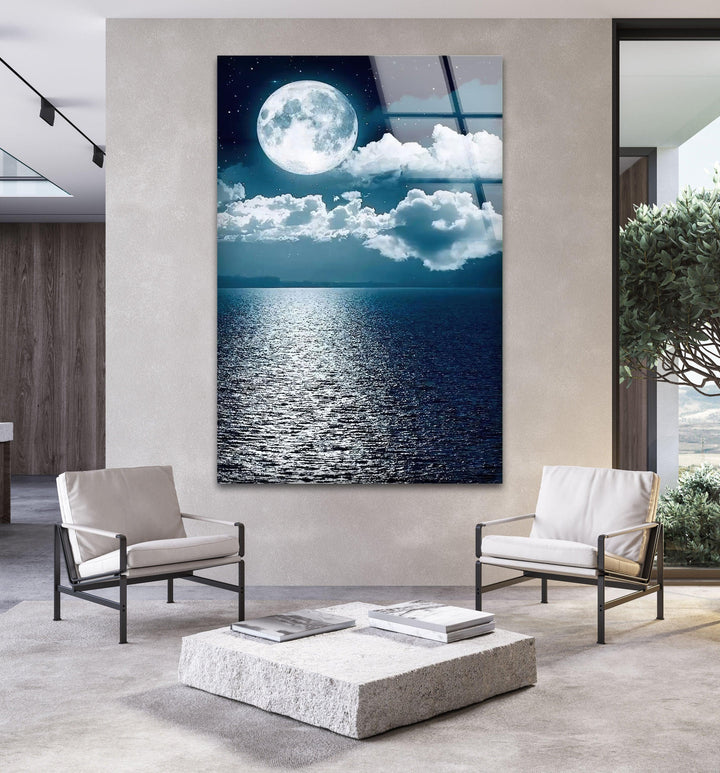 Glass wall art with a bright full moon illuminating calm ocean waves.
