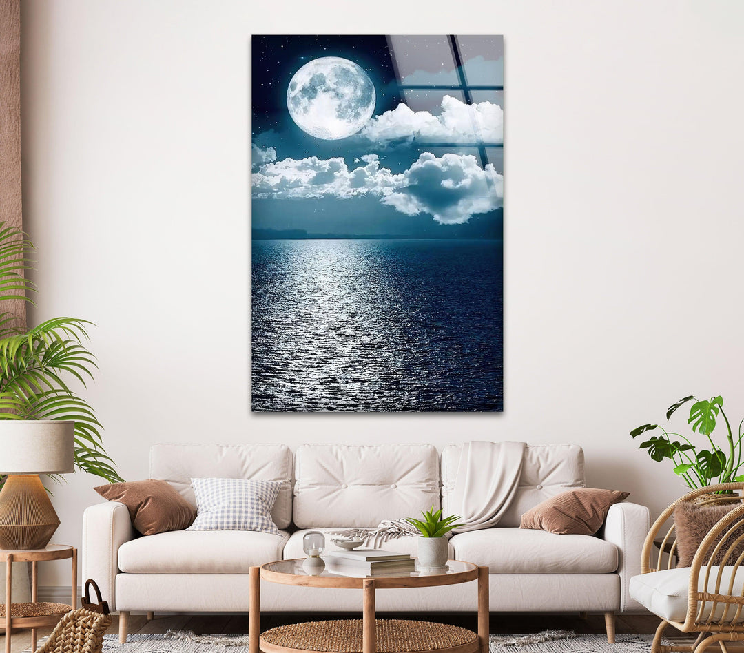 Glass wall art featuring a stunning full moon reflecting over the ocean.
