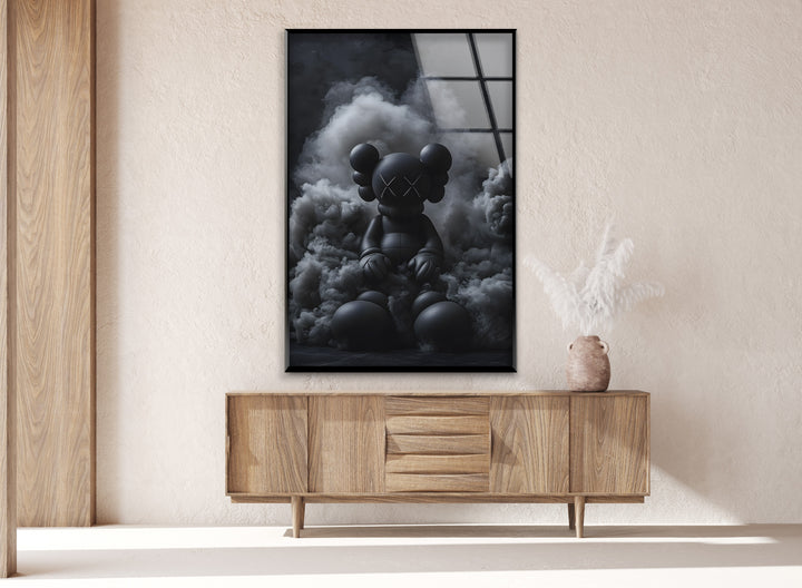 A bold monochrome glass wall art piece showcasing a KAWS-inspired figure with a moody aesthetic.
