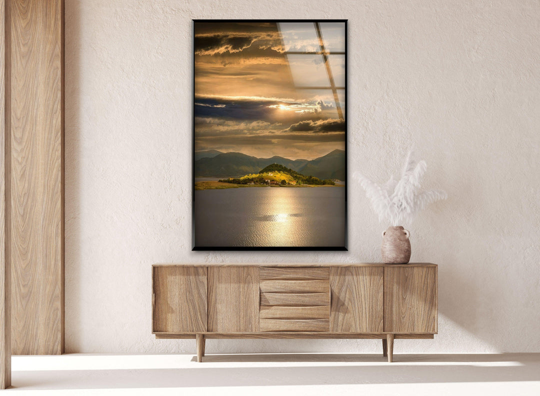 Glass wall art displaying a peaceful lakeside scene with warm golden tones.
